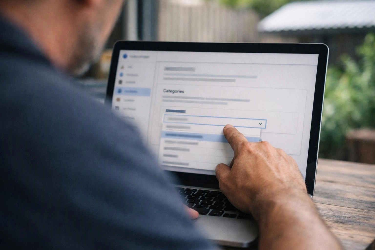 A person taps a laptop dropdown menu on a web form outdoors